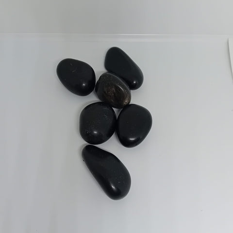 Black Agate Tumbled Stone showcasing smooth, polished crystals in black and brown hues, known for their ability to provide protection, strength, and emotional resilience.