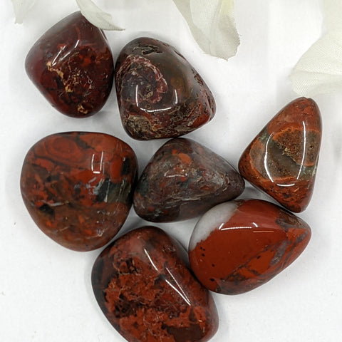 Brecciated Jasper Tumbled Stones featuring smooth, polished crystals with vibrant red, orange, and brown hues, known for their grounding energy, strength-enhancing properties, and ability to support emotional healing.