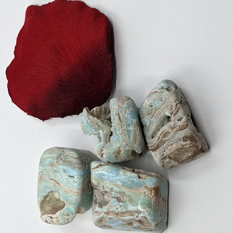 Caribbean Blue Calcite Tumbled Stones showcasing smooth, polished crystals with soft blue and tan hues, known for their calming properties and ability to enhance relaxation and emotional healing.