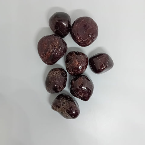 Garnet Tumbled Stone showcasing smooth, polished crystals in deep red hues, known for their ability to promote strength, passion, and emotional healing.