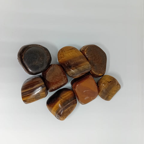 Gold Tiger's Eye Tumbled Stone showcasing smooth, polished crystals with golden brown stripes, known for their ability to boost confidence, courage, and mental clarity.