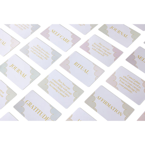 Spread of LSW Mind Cards New Mum Edition featuring categories like Self Care, Ritual, Journal, and Gratitude, with soft pastel accents and gold text.