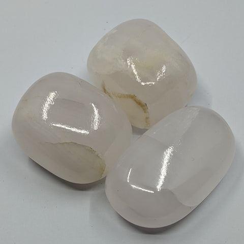 Mangano Calcite Tumbled Stone showcasing smooth, polished crystals in soft pink hues, known for their ability to promote love, emotional healing, and self-compassion.
