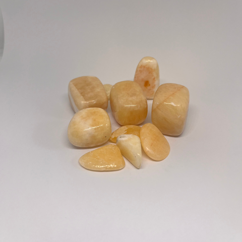 Orange Calcite Tumbled Stones featuring smooth, polished crystals in soft orange and peach hues, known for their energizing properties and ability to enhance creativity and vitality.