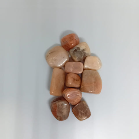 Peach Moonstone Tumbled Stone showcasing smooth, polished crystals in soft peach hues, known for their ability to promote emotional healing, intuition, and new beginnings.