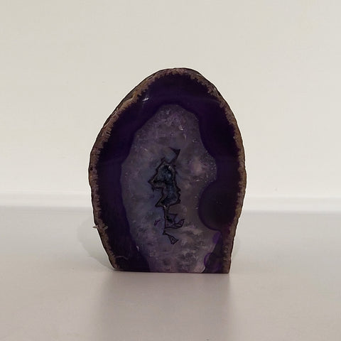 Polished Purple Agate Geode on white background, known for its ability to enhance intuition, spiritual awareness, and mental clarity