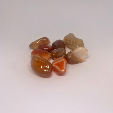 Red River Chalcedony Tumbled Stones with smooth, glossy surfaces featuring warm tones of red, orange, and cream, known for promoting emotional healing, balance, and fostering a sense of calm and stability.