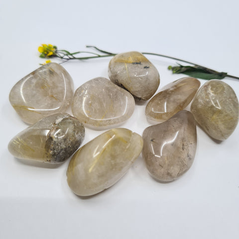 Rutilated Quartz Tumbled Stone showcasing smooth, polished crystals with golden rutile inclusions, known for their ability to amplify energy, promote clarity, and support spiritual growth.