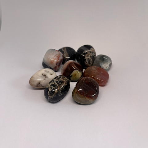 Sardonyx Tumbled Stones featuring a variety of rich earthy tones, including reds, blacks, and browns, showcasing its vibrant banding patterns and smooth polished finish.