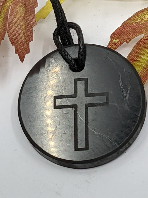 Shungite cross pendant necklace on a white background, combining spiritual protection and grounding energy.