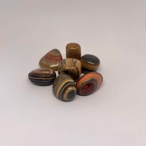 Silver Leaf Jasper Tumbled Stones featuring smooth, striped patterns in earthy tones of brown, red, yellow, and black, known for enhancing creativity and encouraging positive change.