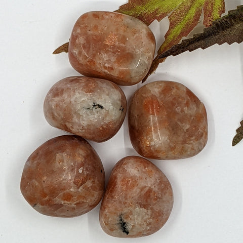 Sunstone Tumbled Stone showcasing smooth, polished crystals in orange and gold hues, known for their ability to promote joy, abundance, and personal power.