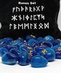 Blue onlyx rune stones with golden symbols scattered in front of a black pouch featuring runic designs, showcasing their smooth surfaces and intricate markings.