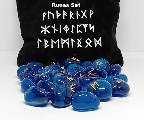 Blue onlyx rune stones with golden symbols scattered in front of a black pouch featuring runic designs, showcasing their smooth surfaces and intricate markings.