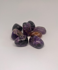 Charoite Tumbled Stones showcasing smooth, polished crystals in rich purple hues with swirling patterns, known for their ability to promote spiritual transformation, inner peace, and emotional healing.