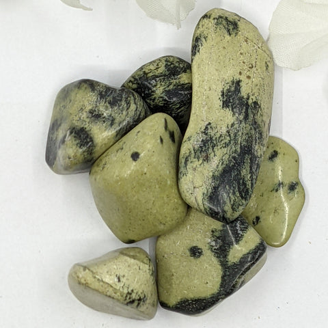 Chytha Serpentine Tumbled Stones displaying smooth, polished crystals in olive green with black veins, known for their grounding energy, healing properties, and ability to enhance spiritual growth.