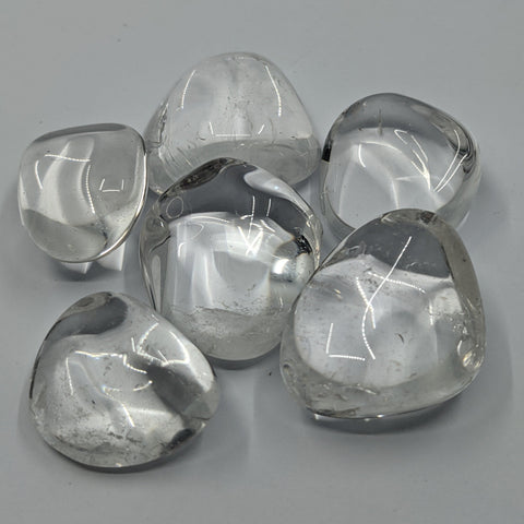 Clear Quartz Tumbled Stones displaying smooth, polished crystals with a transparent, glass-like appearance, known for amplifying energy, promoting clarity, and enhancing healing practices.