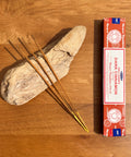 Satya Dark Cinnamon Incense Sticks 15g box on a wooden background, offering a rich and comforting fragrance.