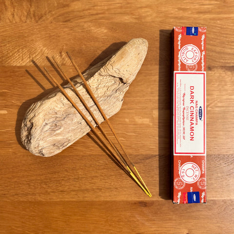 Satya Dark Cinnamon Incense Sticks 15g box on a wooden background, offering a rich and comforting fragrance.