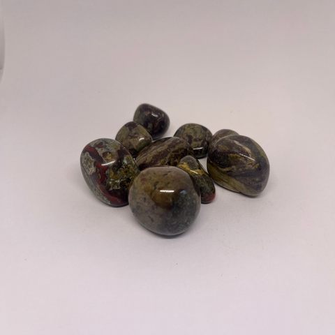 Dragon Blood Jasper Tumbled Stones in shades of red, green, and yellow, displaying smooth polished surfaces, arranged in a group on a white background.