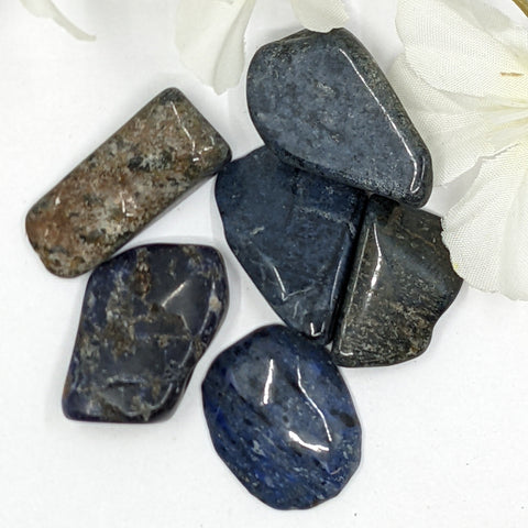 Dumortierite Tumbled Stones displaying smooth, polished crystals in deep blue and violet hues, known for enhancing mental clarity, emotional balance, and promoting communication and patience.