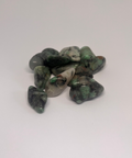 Emerald Tumbled Stones showcasing vibrant green hues with subtle veins of other colors, arranged in a group on a white background.