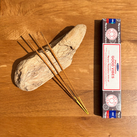 Satya Good Vibes Nag Champa Incense Sticks 15g box on a wooden background, offering a joyful and uplifting fragrance.