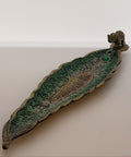 Green metallic incense burner with gem and elephant detail on white background