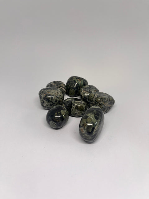 Kambaba Jasper Tumbled Stones displaying smooth, polished crystals with swirling green and black patterns, known for their grounding properties and ability to promote relaxation, inner peace, and emotional healing.