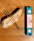 Satya Money Matrix Nag Champa Incense Sticks 15g box on a wooden background, designed to attract abundance.