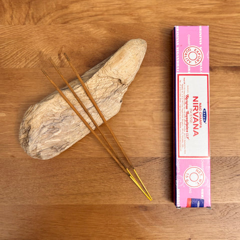 Satya Nirvana Incense Sticks 15g box on a wooden background, designed to deepen meditation and spiritual awareness.