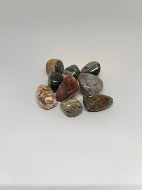 Ocean Jasper Tumbled Stones in a variety of warm colors, including greens, reds, and yellows, with distinct circular patterns and smooth, polished surfaces showcasing the stone's natural beauty.