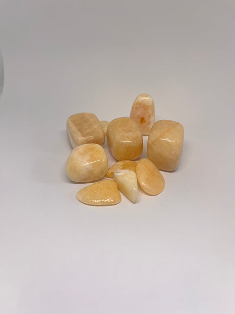 Orange Calcite Tumbled Stones featuring smooth, polished crystals in soft orange and peach hues, known for their energizing properties and ability to enhance creativity and vitality.