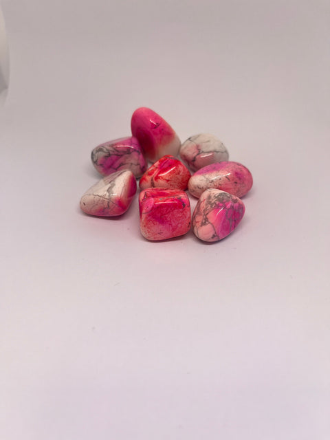 Pink Howlite Tumbled Stones in various smooth shapes, displaying vibrant pink tones mixed with white veins, creating a striking contrast and natural marbled effect.