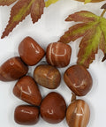 Red Zebra Jasper Tumbled Stones displaying smooth, polished crystals in vibrant red and earthy brown with natural banding, known for their grounding energy and ability to promote balance and stability.