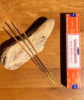 Satya Sandalwood Incense Sticks 15g box on a wooden background, offering a classic woody aroma for relaxation.