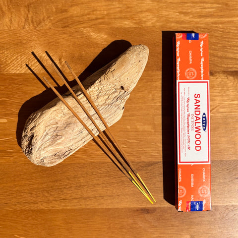 Satya Sandalwood Incense Sticks 15g box on a wooden background, offering a classic woody aroma for relaxation.