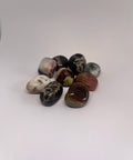 Sardonyx Tumbled Stones featuring a variety of rich earthy tones, including reds, blacks, and browns, showcasing its vibrant banding patterns and smooth polished finish.