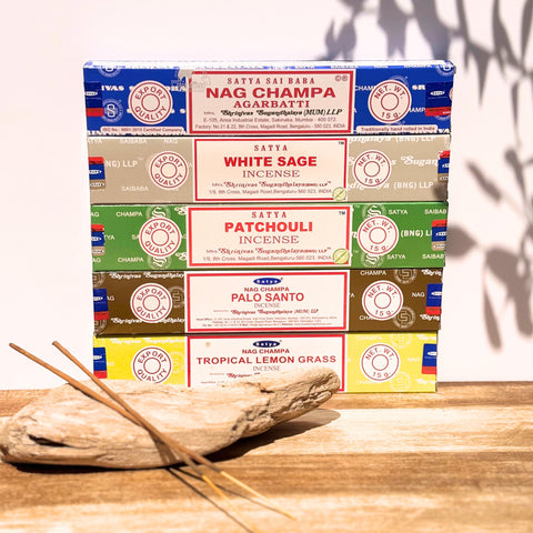 Satya Incense Best Seller Bundle showcasing Nag Champa Satya Incense, Satya White Sage, Satya Patchouli, Satya Palo Santo and Satya Tropical Lemongrass on a piece of driftwood with a white background.