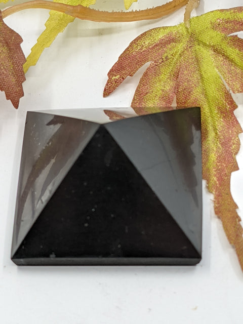 Shungite pyramid 3cm on a white background, for energy amplification and protection.