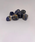 Sodalite Tumbled Stones featuring a mix of blue and white hues, with smooth polished surfaces, arranged in a group on a white background.