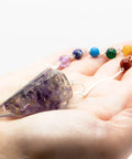 Amethyst orgonite chakra pendulum held in hand showing size and crystal detail for divination and energy work