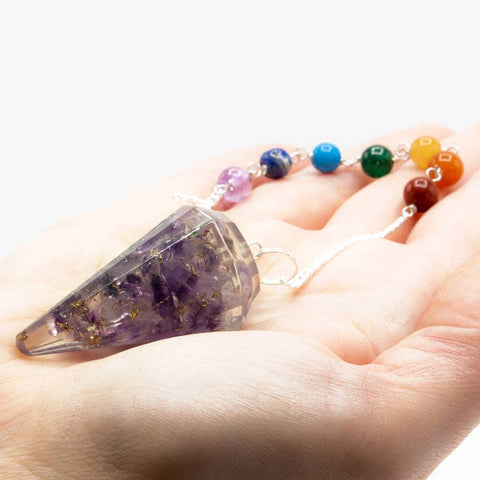 Amethyst orgonite chakra pendulum held in hand showing size and crystal detail for divination and energy work