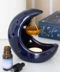 Blue Crescent Moon Hanging Oil Burner with tealight lit, gold bowl, and celestial decor.