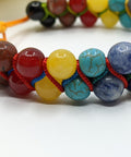 Closeup of Chakra Super Powerball Bracelet with polished gemstone beads on a white background.