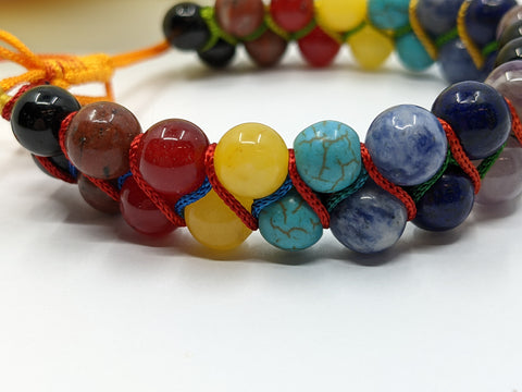 Closeup of Chakra Super Powerball Bracelet with polished gemstone beads on a white background.