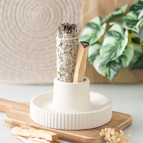 Cream Ribbed Smudge Bowl displayed with sage and palo santo on a wooden surface.