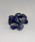 Lapis lazuli tumbled stone showing deep blue with golden pyrite flecks on white background — healing crystals Ireland, Fragrant Heaven