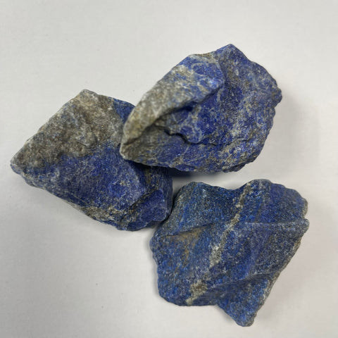 Three raw lapis lazuli pieces showing natural deep blue colour and gold pyrite flecks on white background — Fragrant Heaven