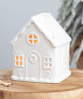 White ceramic gingerbread house tealight holder with warm glow
